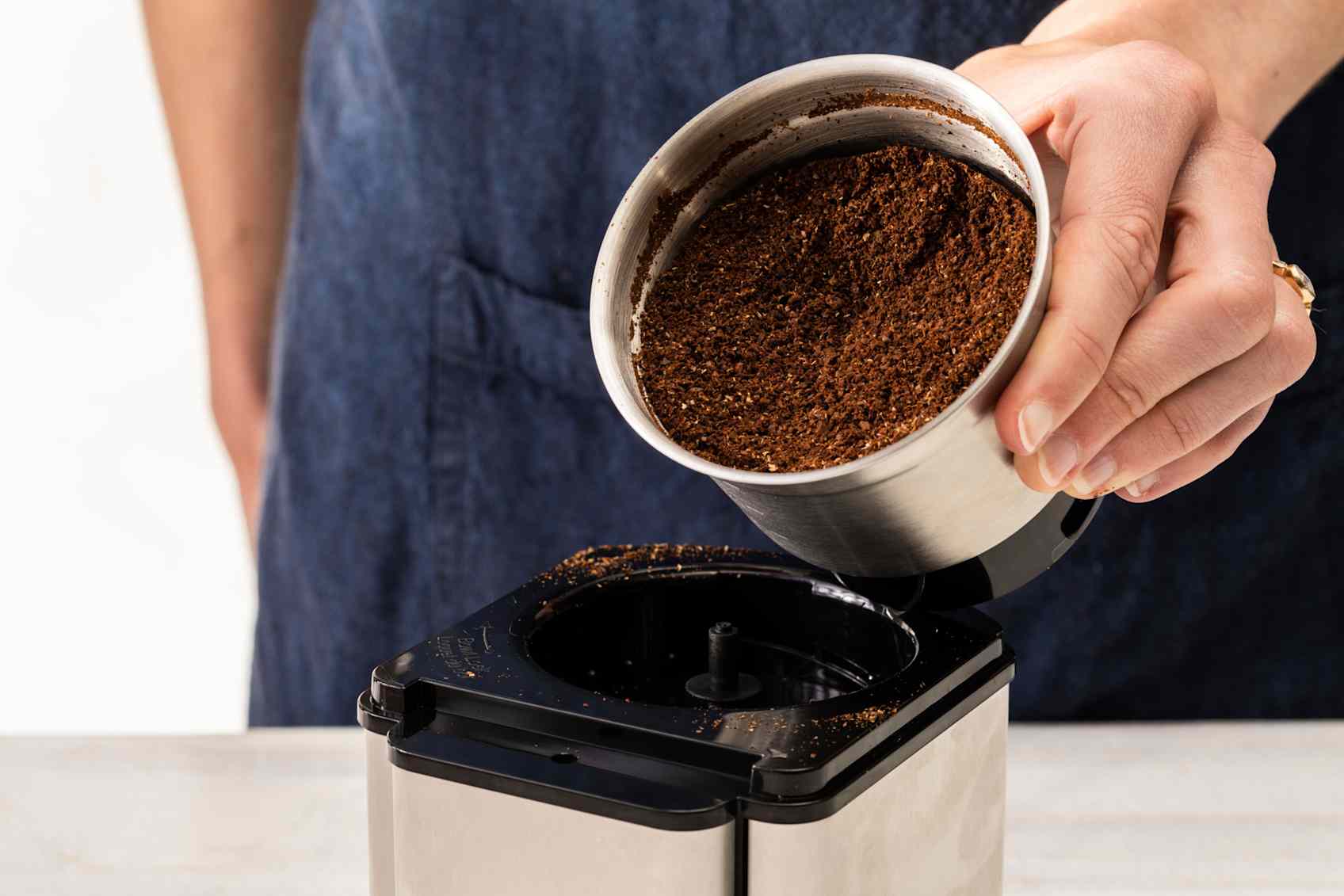 A person is tilting a grinding bowl full of ground coffee towards the camera.